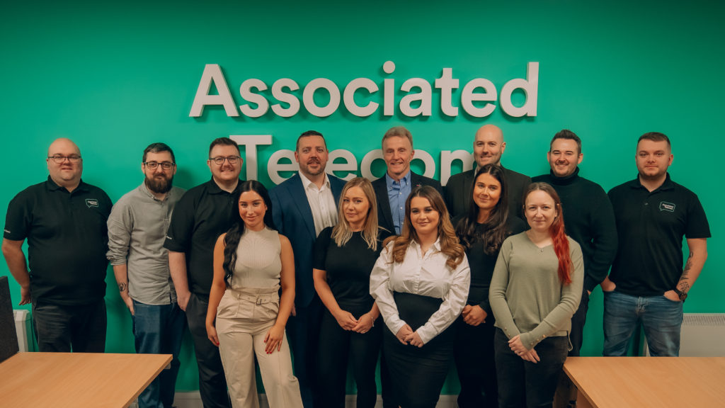 Images of the Associated Telecom team in their office with a green wall and the words Associated Telecom behind them.