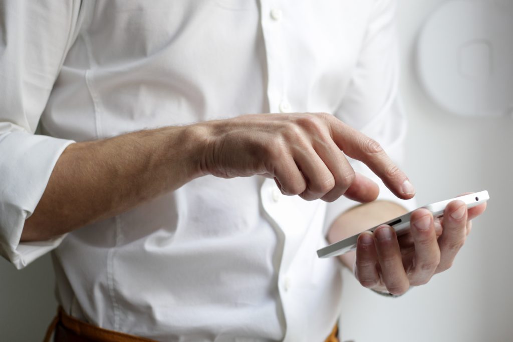 Image of man in white shirt using a mobile phone