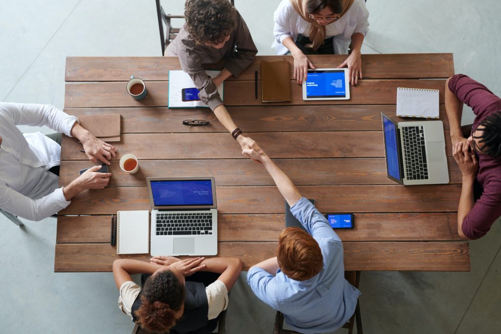 Image shows a work team of 6 people having a meeting around the table. 