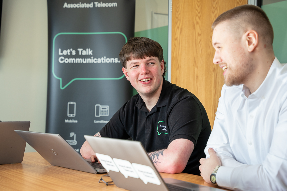 Associated Telecom colleagues discussing work in a meeting room.