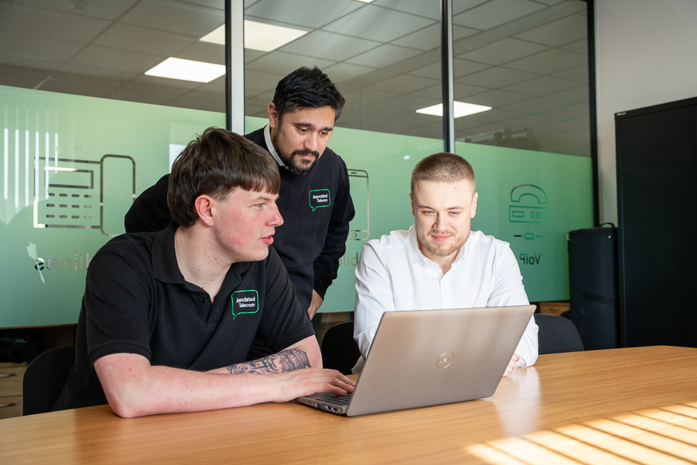Team members collaborating at a laptop in the office.