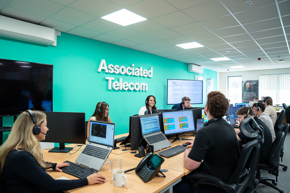 Team collaborating around desks in a telecom office.