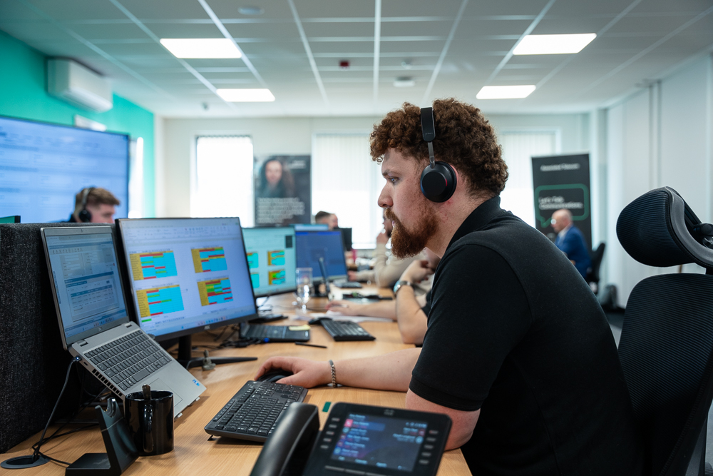 Associated Telecom customer support agent working in a modern open-plan office.