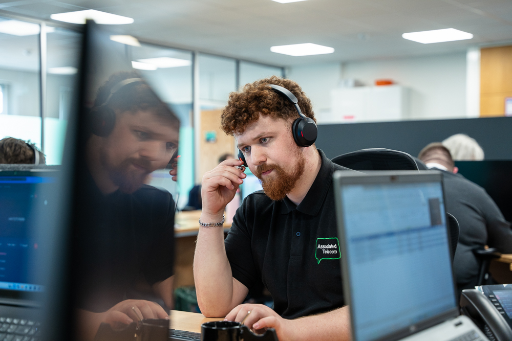 Associated Telecom customer support team working together in a modern office.