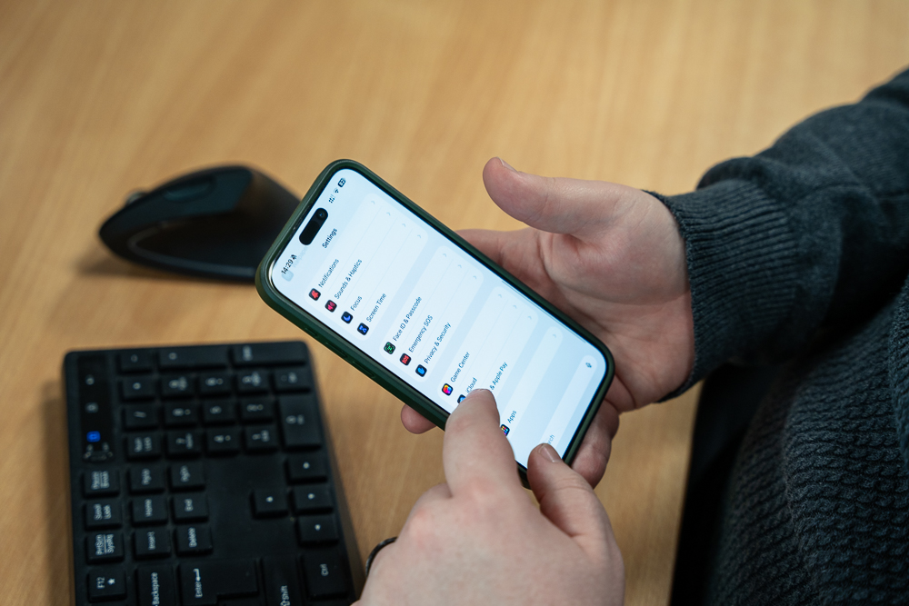 Associated Telecom employee checking a smartphone at a desk.