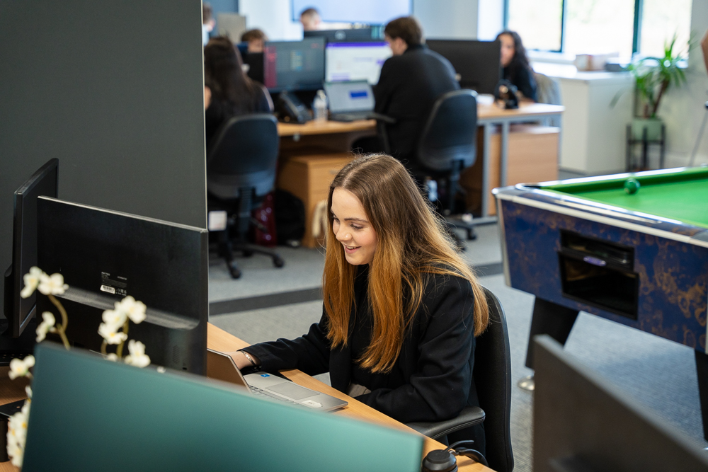 Associated Telecom employee working in a busy open-plan office.