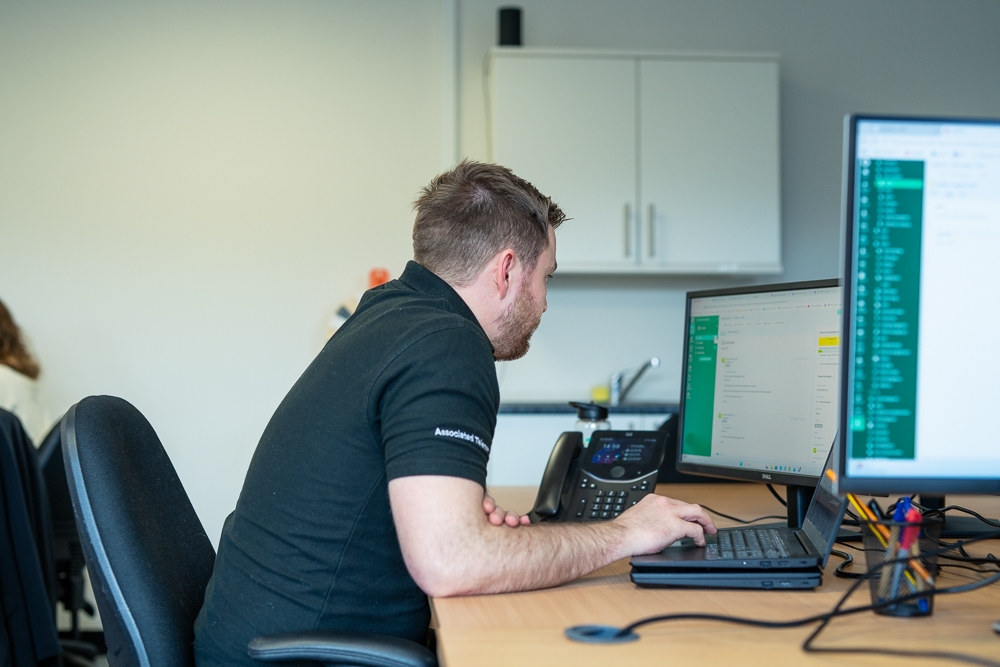 Associated Telecom support specialist working at a dual-monitor desk.