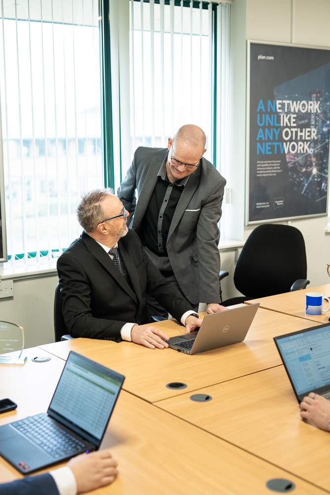 Associated Telecom staff working together around a meeting table.