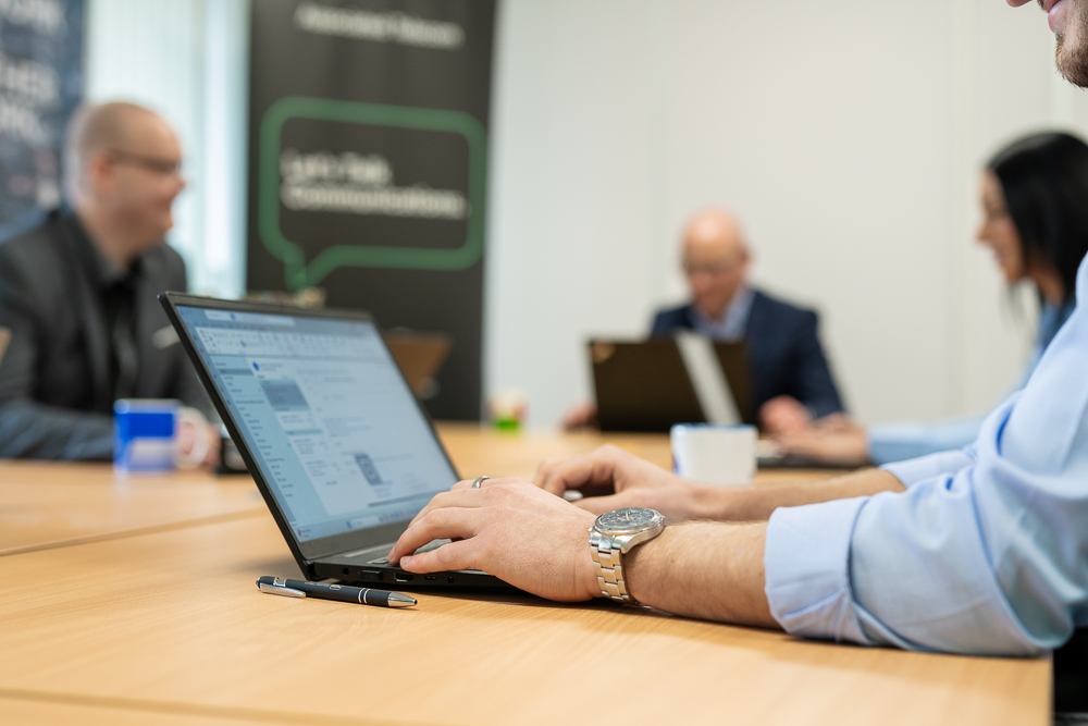Associated Telecom business professional using a laptop at a desk.