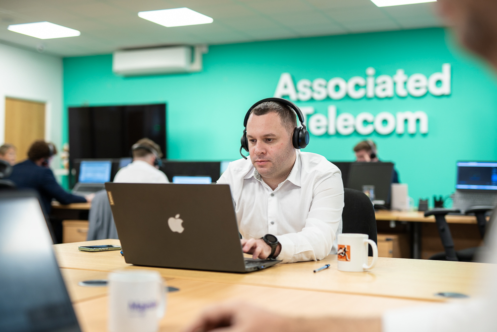 Associated Telecom staff member working on a laptop in the office.