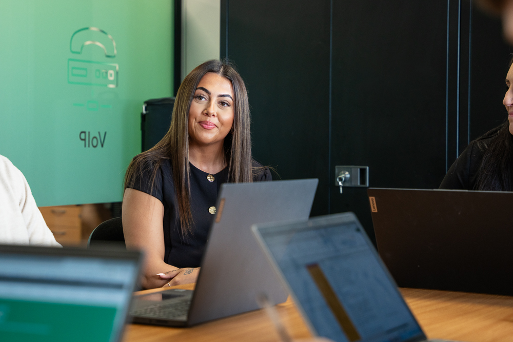 Associated Telecom office employee focused on laptop work.