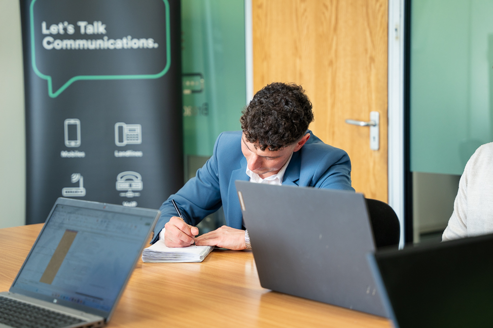 Associated Telecom office worker focused on a notepad at a desk.