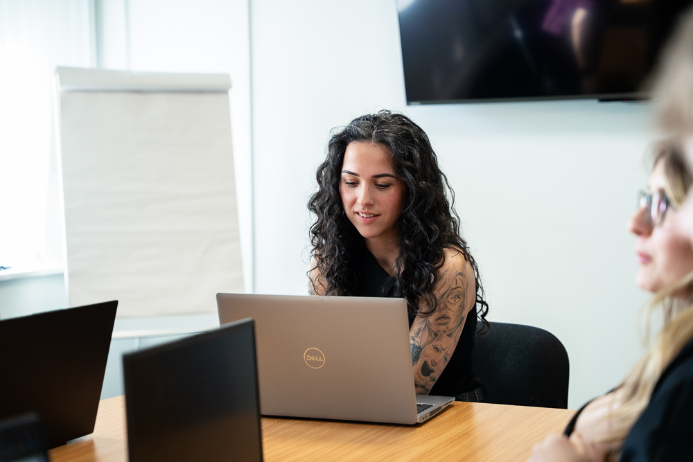 Associated Telecom staff member checking work on a laptop.